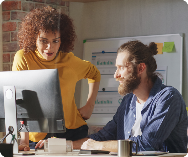 Two professionals collaborating at a computer in an office setting.